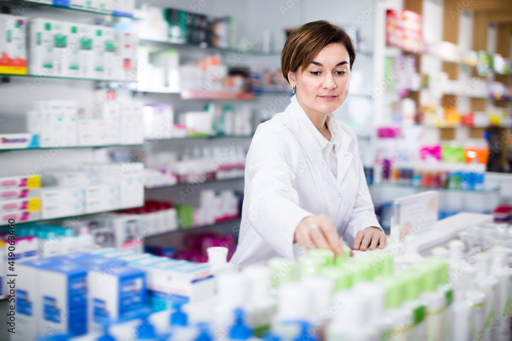 Young female pharmacist arranging assortment of products in pharmacy