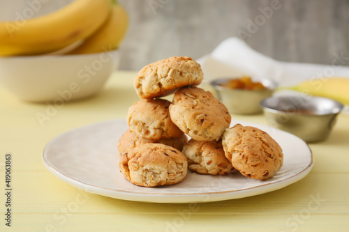 Plate with tasty banana cookies on color wooden background