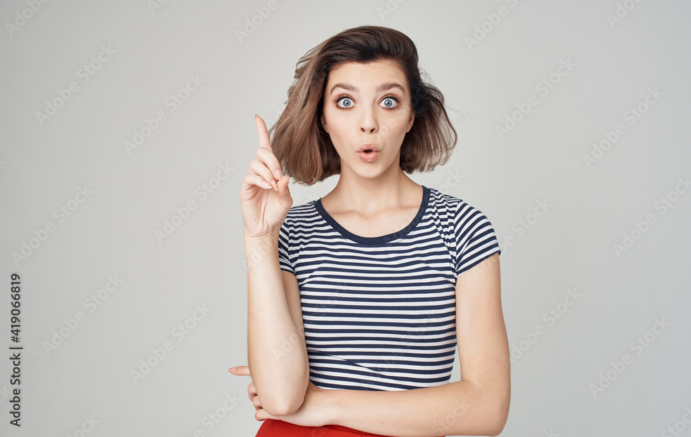 Obraz premium pretty model woman in striped t-shirt gesturing with hands on gray background Copy Space