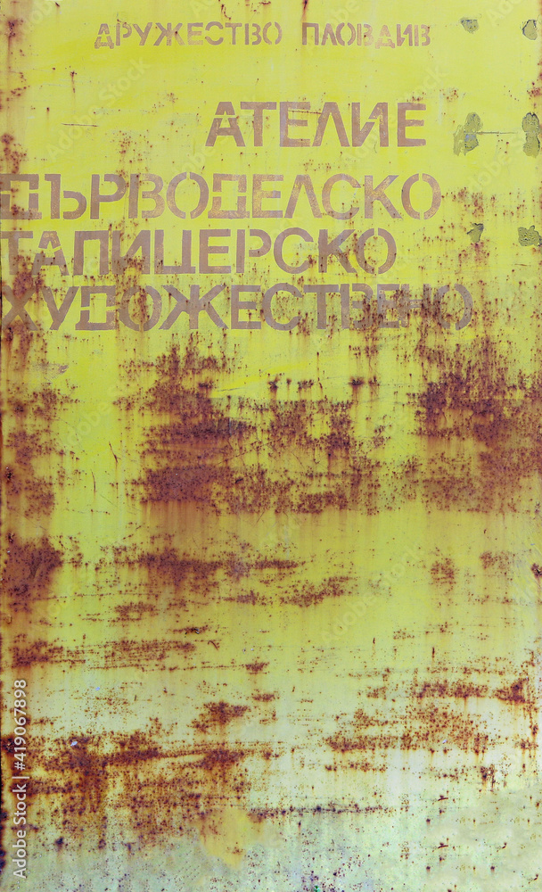 old yellow metal door with rust, scratches and words with cyrillic leters - steampunk textured background