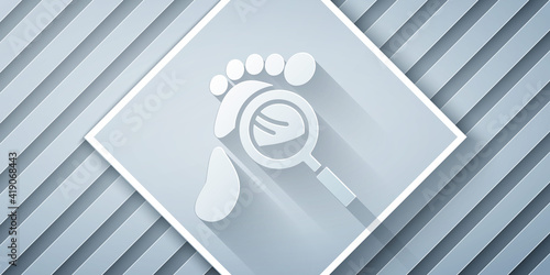 Paper cut Magnifying glass with footsteps icon isolated on grey background. Detective is investigating. To follow in the footsteps. Paper art style. Vector.