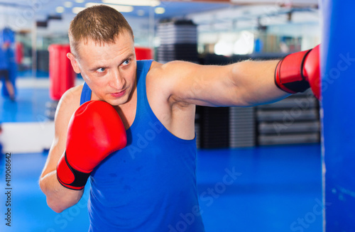 Potrait of cheerful positive man boxer who is training in gym.
