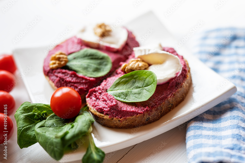 red beetroot brie goat cheese walnut dip sandwich bread spread with salad on white porcelain plate 
