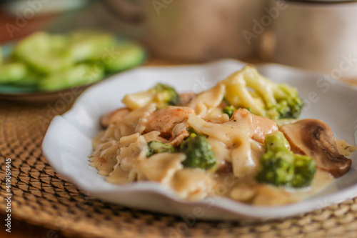 Pasta with fried mushrooms and chicken. Cheese, broccoli, champignons on the table.