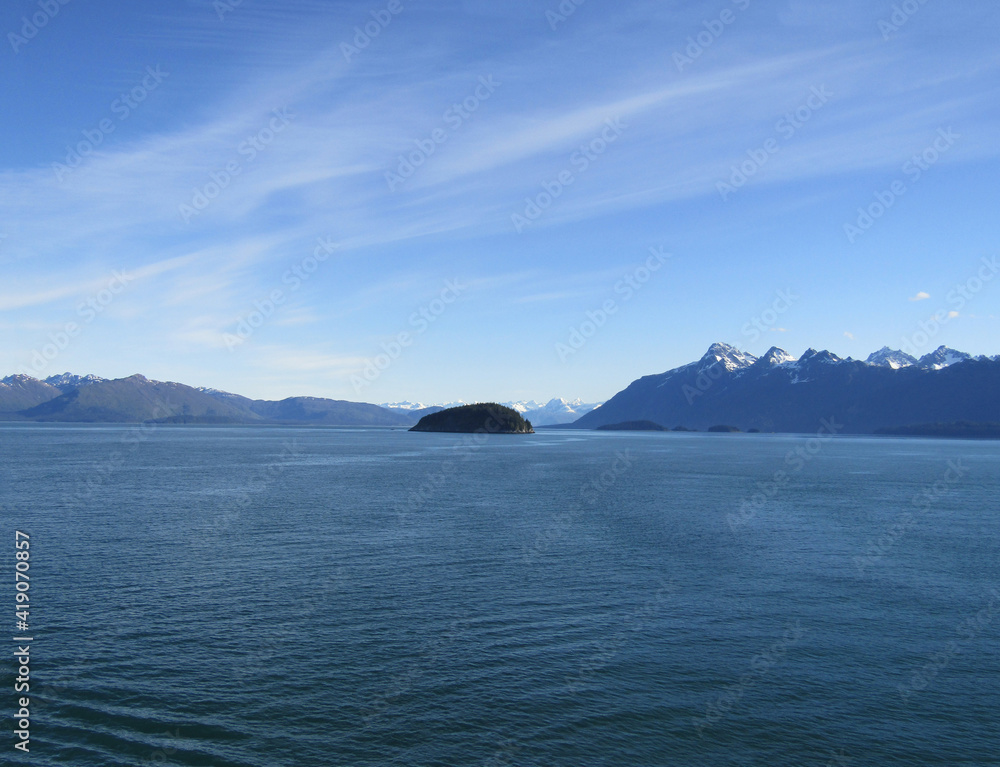 View of an island near glacier and snow covered mountains from an Alaska cruise ship.