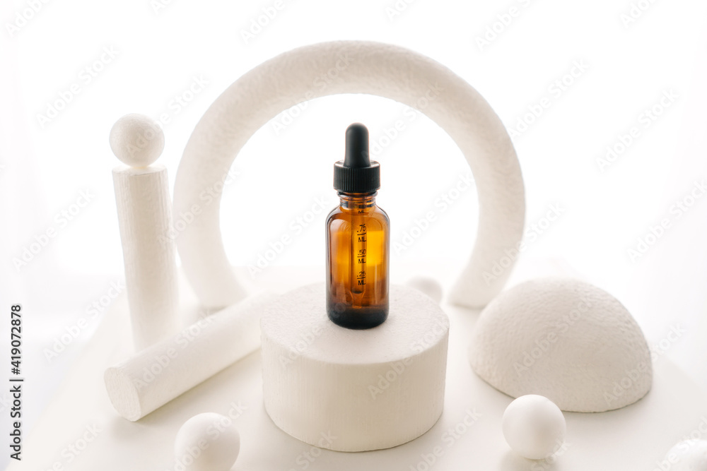 Blank amber glass face serum bottle on white background. Natural cosmetics, alternative medicine, minimal concept. Abstract background with different shapes.