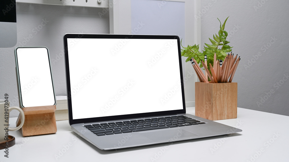Modern work place with computer laptop and smart phone with blank screen on white desk. Modern work place with computer laptop and smart phone with blank screen on white desk.