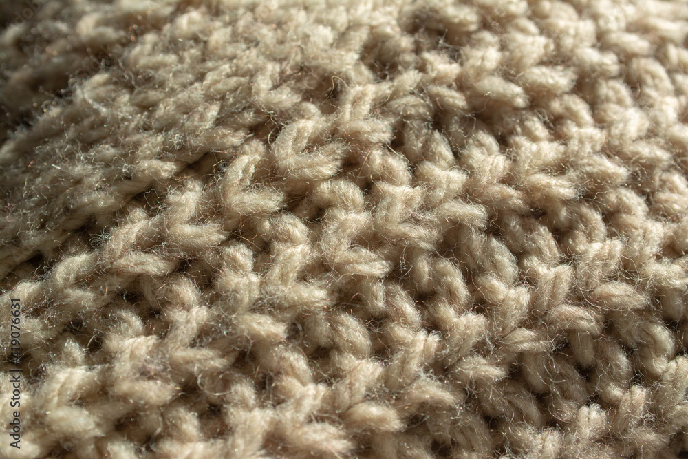 Diagonal closeup of a part of the central twist of a large knitted jumper. English knit. Beige, natural colour. Diagonal closeup of a part of the central twist of a large knitted jumper. English knit. Beige, natural colour.
