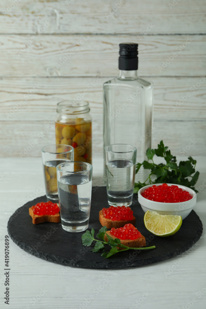 Shots of vodka and tasty snacks on white wooden background Shots of vodka and tasty snacks on white wooden background