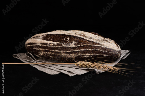 Obraz na płótnie Homemade sourdough rye bread with caraway seeds and spikelet on gray textile napkin on dark background. Copy space. w salonie