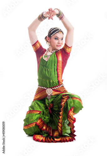 Beautiful young female Bollywood dancer dressed in green and orange folded dress posing as cobra
