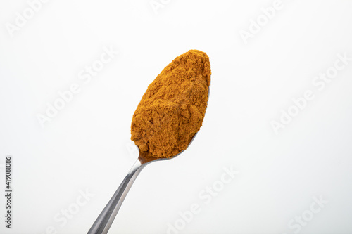 Silver teaspoon with cumin powder on white background