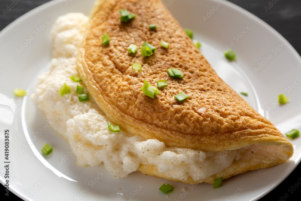 Homemade Fluffy Omelet on a white plate on a black background, side view. Close-up. Homemade Fluffy Omelet on a white plate on a black background, side view. Close-up.