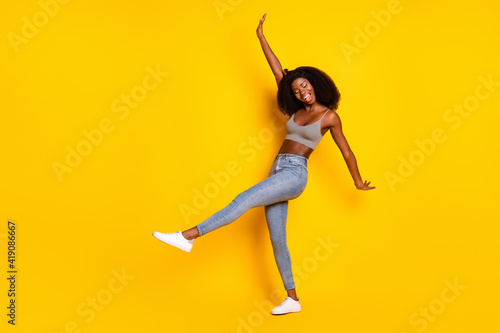 Photo of funny funky lovely lady dance have fun wear grey cropped top jeans shoes isolated yellow color background