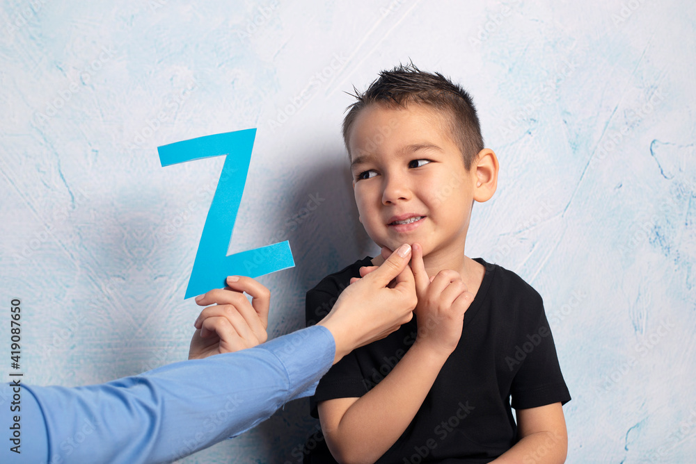 Cute little boy at speech therapist. Blue background in the studio Cute little boy at speech therapist. Blue background in the studio