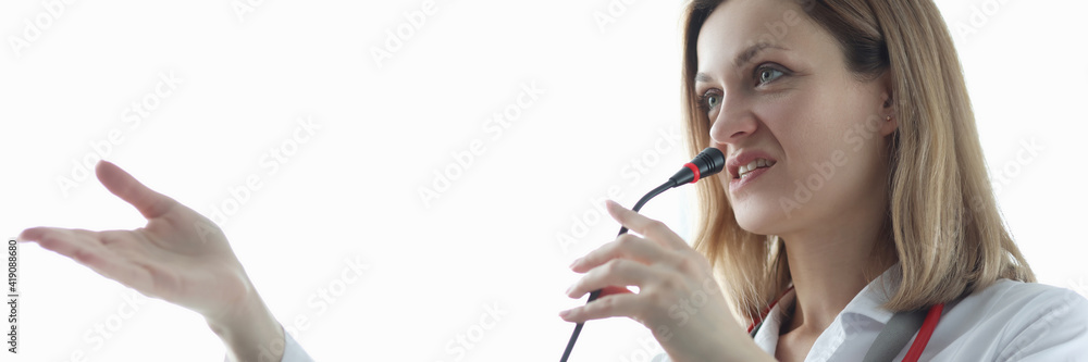 Woman doctor speaking into microphone at presentation Woman doctor speaking into microphone at presentation
