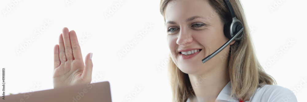 Doctor in headphones with microphone waving his hand at laptop screen Doctor in headphones with microphone waving his hand at laptop screen