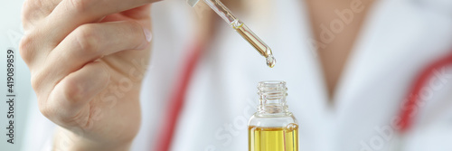Doctor dripping cosmetic oil from pipette closeup