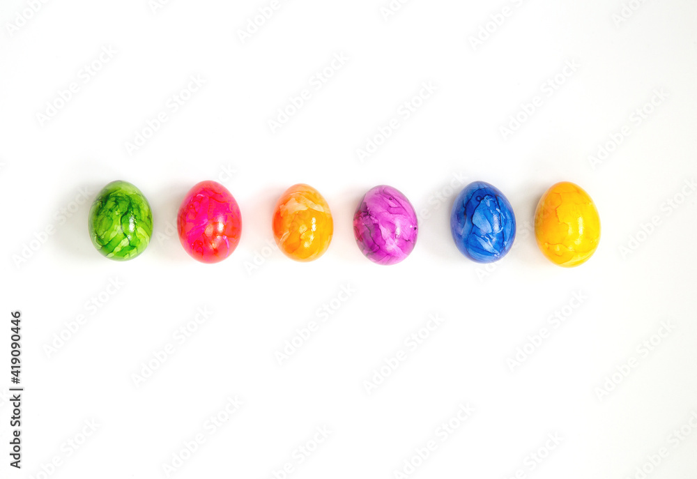 Row of Colorful painted Easter Eggs isolated on white background surrounded with flowers top view background, Happy Easter concept modern design