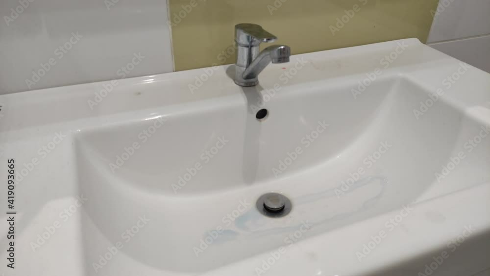 Housekeeper washes with cleaning agent, household chemicals plumbing faucet and washbasin Housekeeper washes with cleaning agent, household chemicals plumbing faucet and washbasin