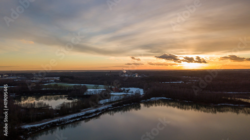 Aerial view of a beautiful and dramatic sunset over a forest lake reflected in the water, landscape drone shot. Blakheide, Beerse, Belgium. High quality photo