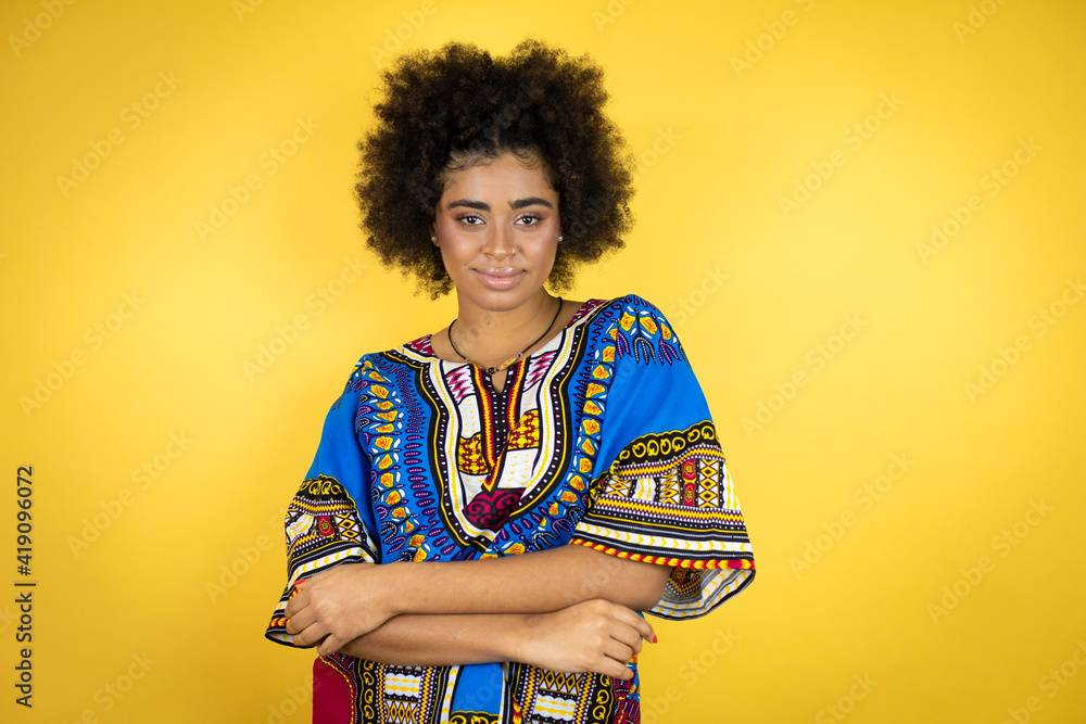 African american woman wearing african clothing over yellow background with a happy face standing and smiling with a confident smile showing teeth