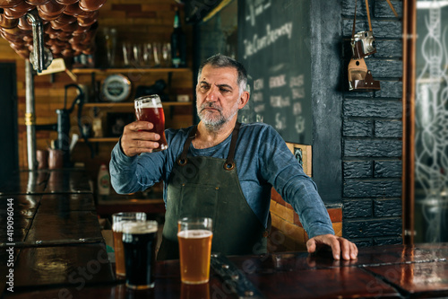 middle aged man bartender serving beer in beer pub