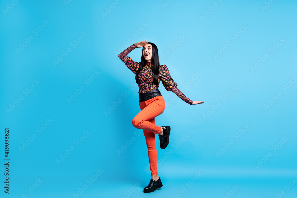 Photo of lady stand one leg look empty space wear flower print shirt pants shoes isolated blue color background