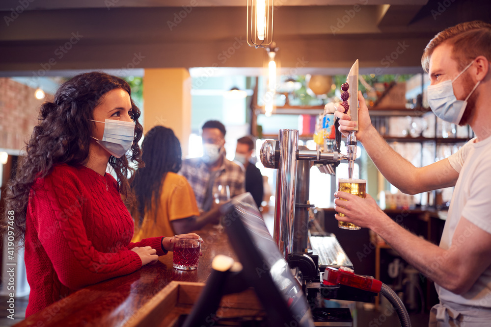Male Bartender Wearing Face Mask Serving Female Customer With Drink During Health Pandemic Male Bartender Wearing Face Mask Serving Female Customer With Drink During Health Pandemic