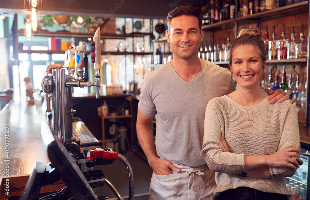Portrait Of Smiling Couple Owning Bar Standing Behind Counter