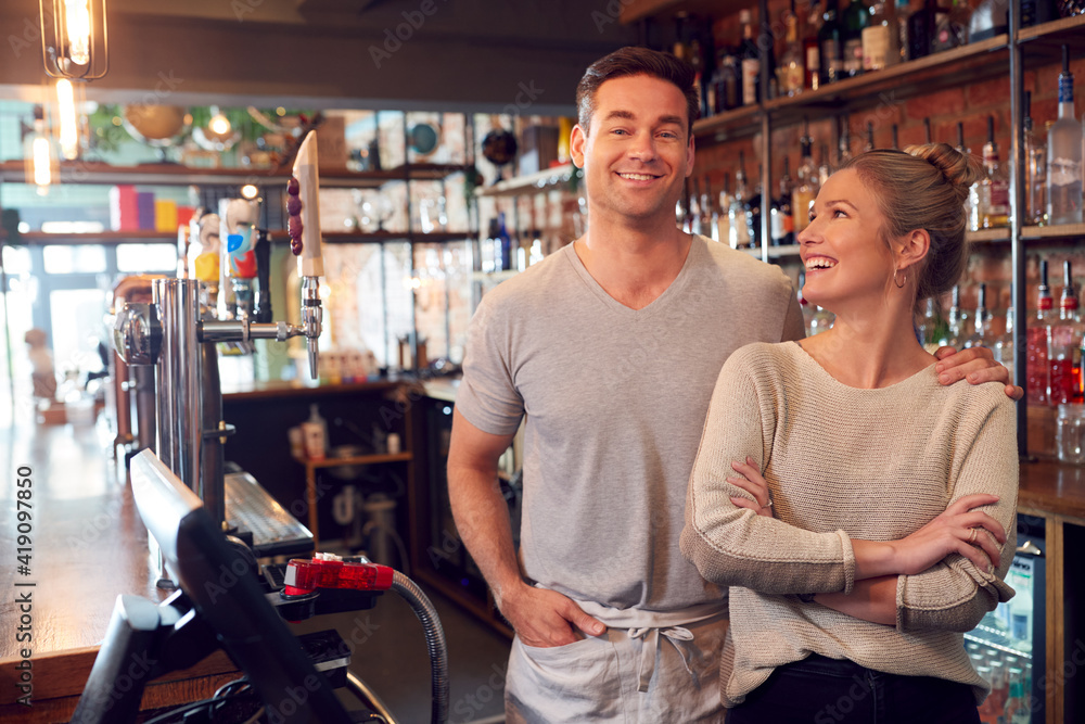 Portrait Of Smiling Couple Owning Bar Standing Behind Counter