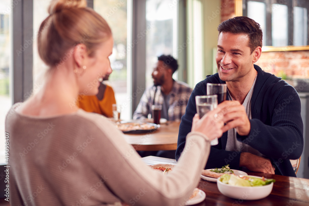 Smiling Couple On Date Making Toast Before Enjoying Pizza In Restaurant Together Smiling Couple On Date Making Toast Before Enjoying Pizza In Restaurant Together