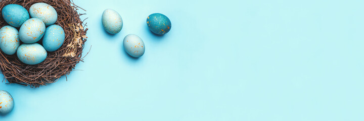 Easter eggs in nest on blue background. Flat lay, top view.