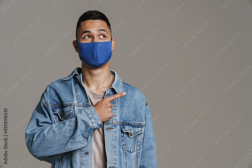 Happy caucasian guy in protective mask pointing finger aside Happy caucasian guy in protective mask pointing finger aside