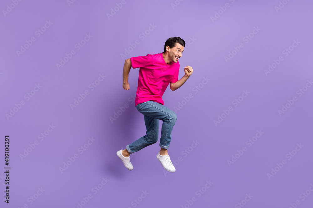 Full size profile side photo of young happy cheerful funky crazy man running in air isolated on purple color background Full size profile side photo of young happy cheerful funky crazy man running in air isolated on purple color background