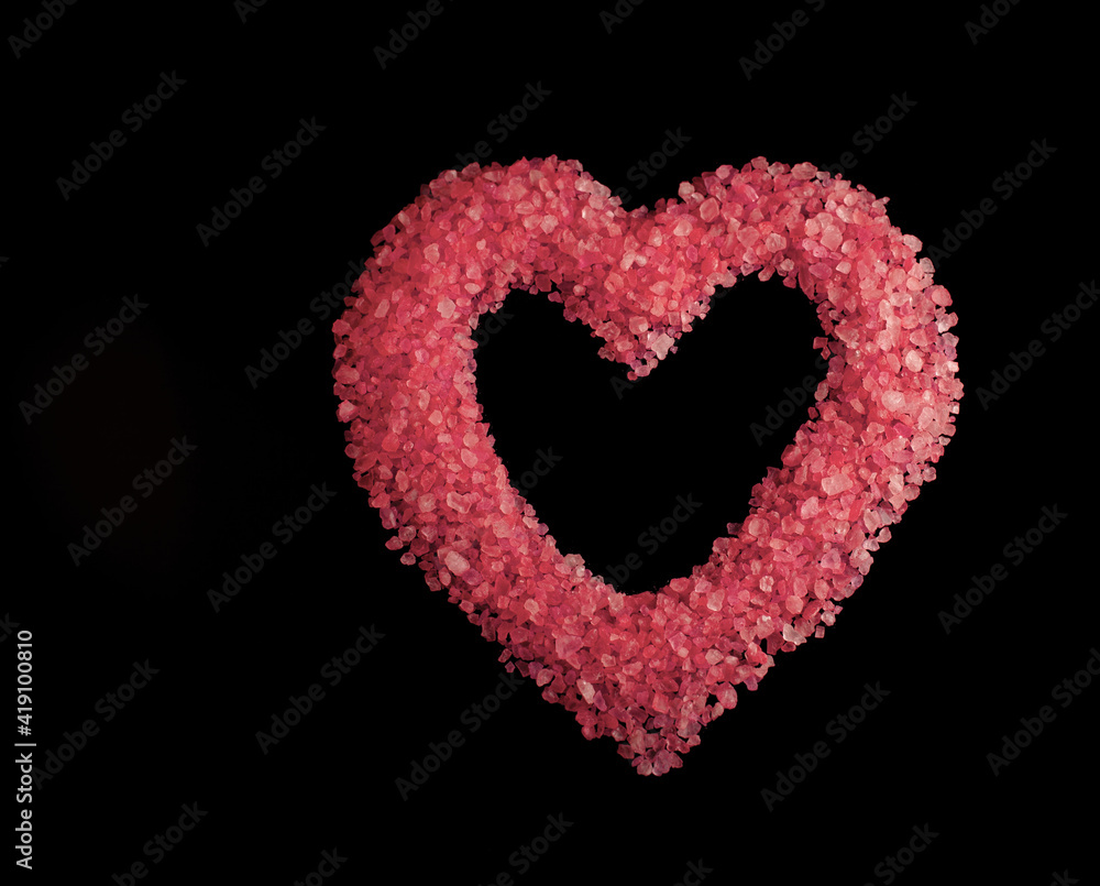 Flat lay on a black background sea salt for a heart shaped pink bath