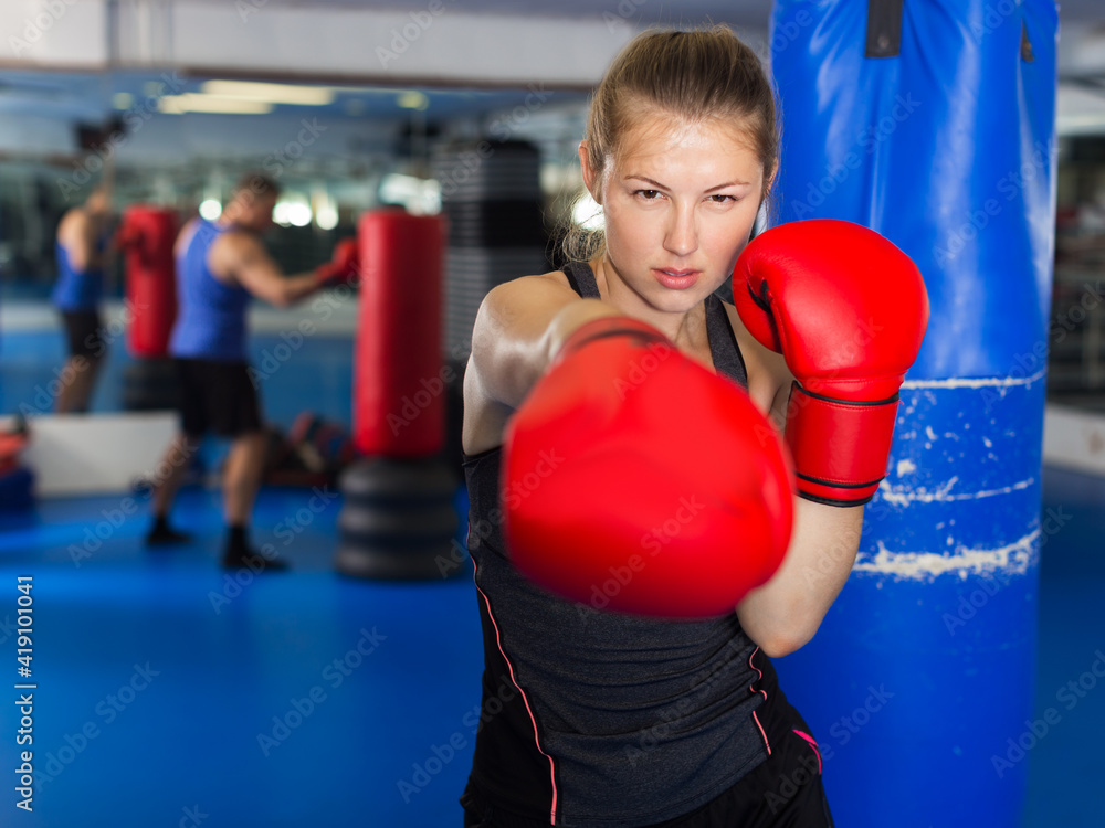 Portrait of young positive woman boxer training in gym