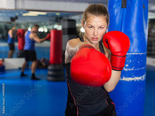 Portrait of young positive woman boxer training in gym © JackF