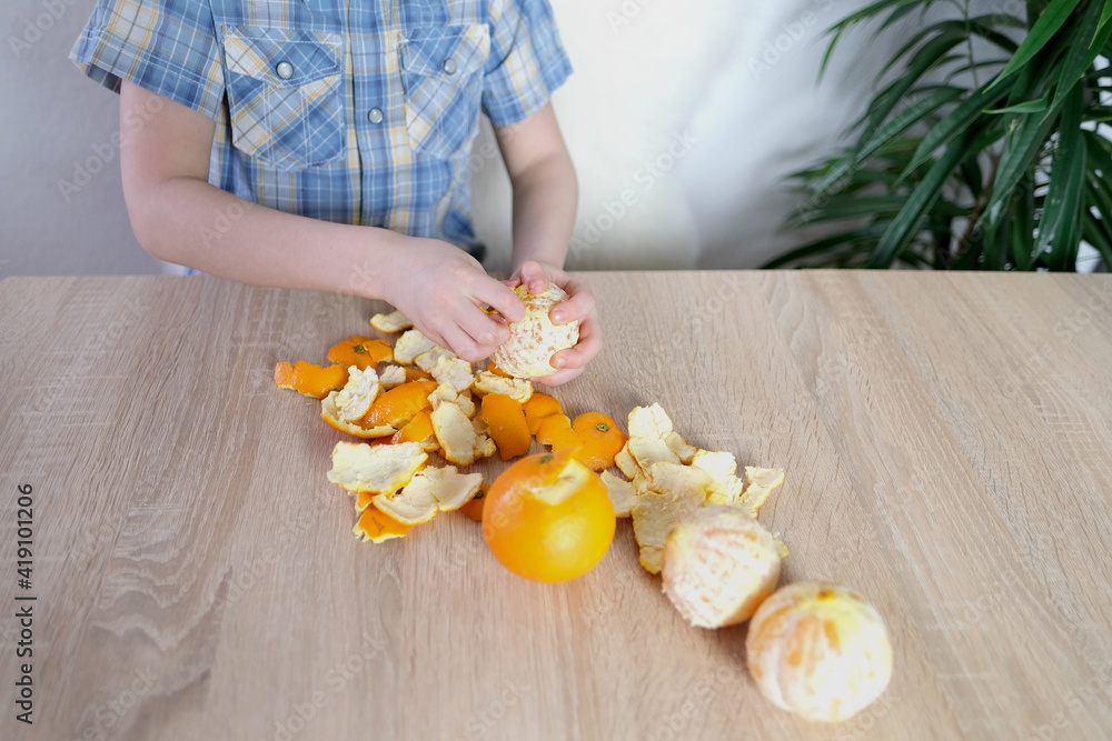 child, boy 6-8 years old peels big orange oranges, the concept of the development of fine motor skills, patience, healthy food, healthy baby food