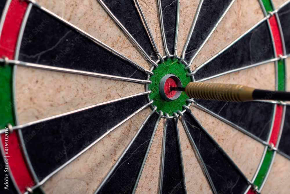 Side view of darts board and arrow hitting bullseye. Side view of darts board and arrow hitting bullseye.