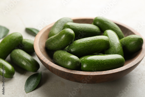 Fotografia Wooden bowl with seedless avocados on grey table, closeup