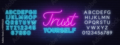 Trust yourself neon inspirational quote. Inspirational glowing lettering. Neon blue and white alphabet on brick wall background.