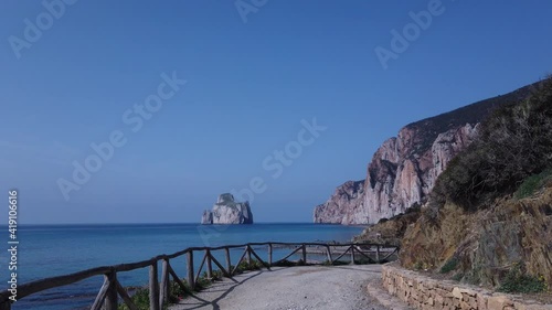 Walking down to the beach in a sunny day in summer. Landscape of Sardinian island sea with azure water, sandy bottom at sunset. Pan di Zucchero, Masua