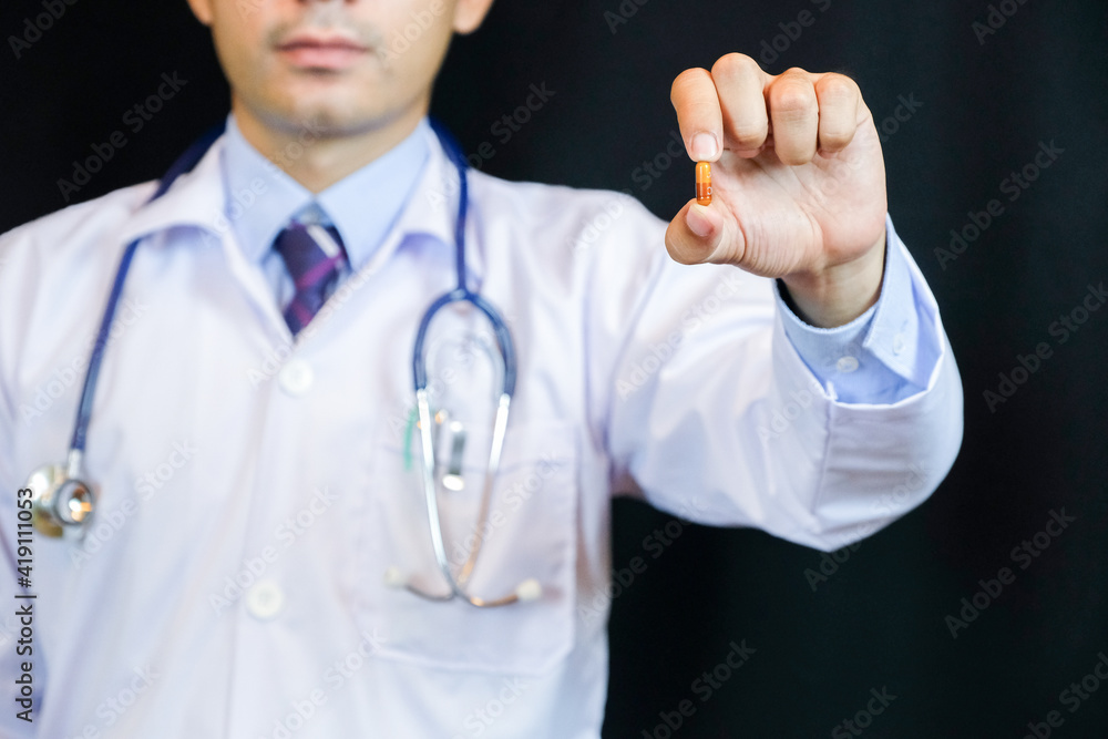 Portrait of confident young medical doctor on black background. He recommended medicine. Portrait of confident young medical doctor on black background. He recommended medicine.