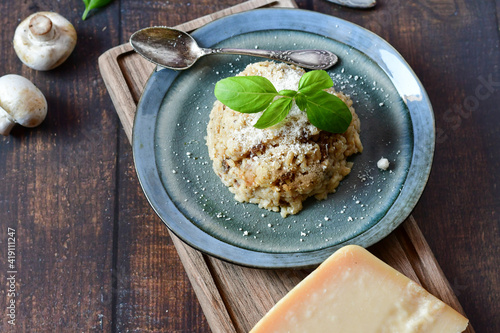 Italian  home made creamy   mushroom risotto with parmesan cheese and fresh basil on rustic background