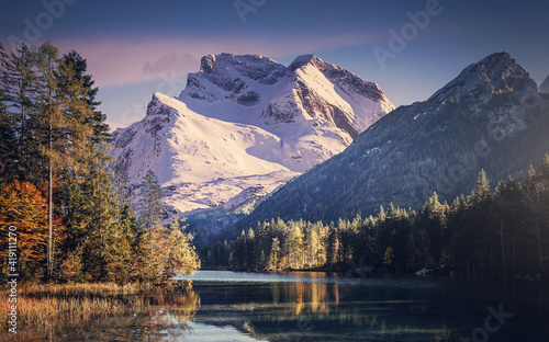 Impressive Autumn landscape during sunset. The fary tale Lake in front of the snowy mount under sunlight. Amazing sunny day on the mountain scenery. concept of an ideal resting place. Creative image.