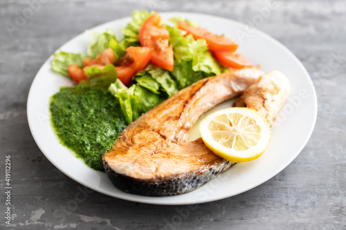 fried salmon with spinach and salad on white plate