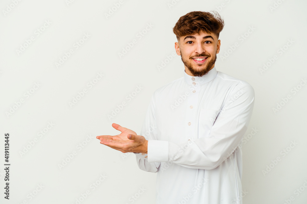 Young Moroccan man wearing a typical arab clothes isolated on white background holding a copy space on a palm.