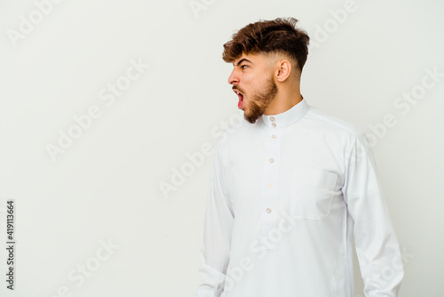 Young Moroccan man wearing a typical arab clothes isolated on white background shouting towards a copy space