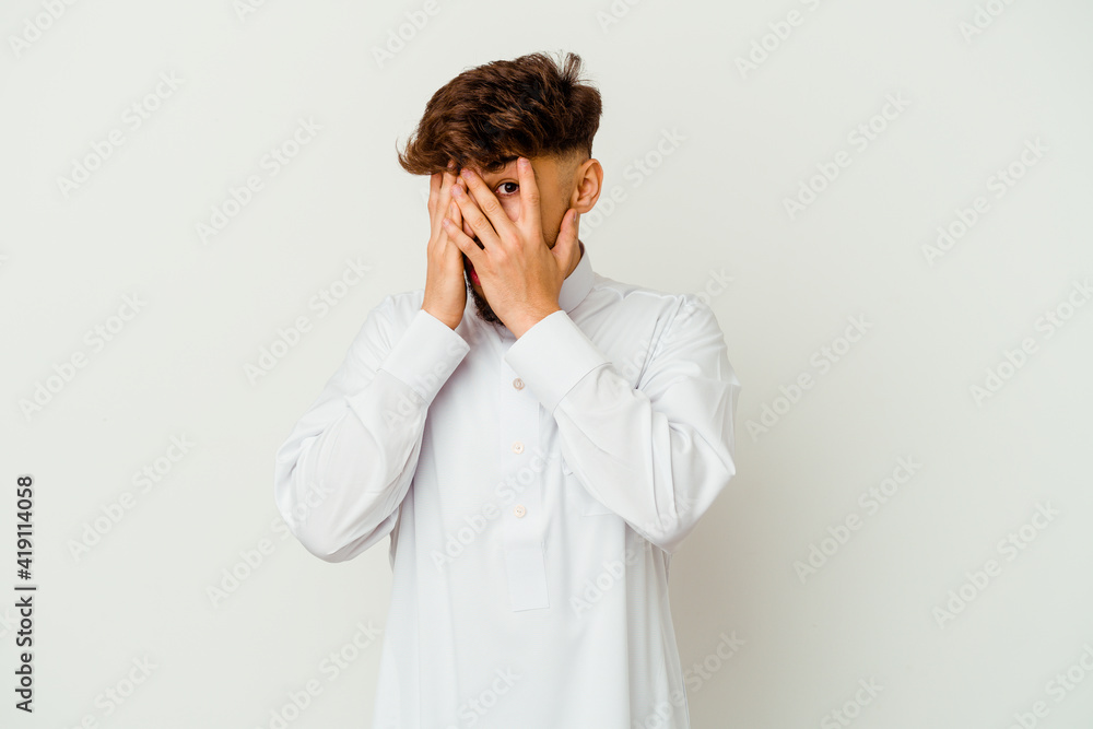 Young Moroccan man wearing a typical arab clothes isolated on white background blink through fingers frightened and nervous. Young Moroccan man wearing a typical arab clothes isolated on white background blink through fingers frightened and nervous.
